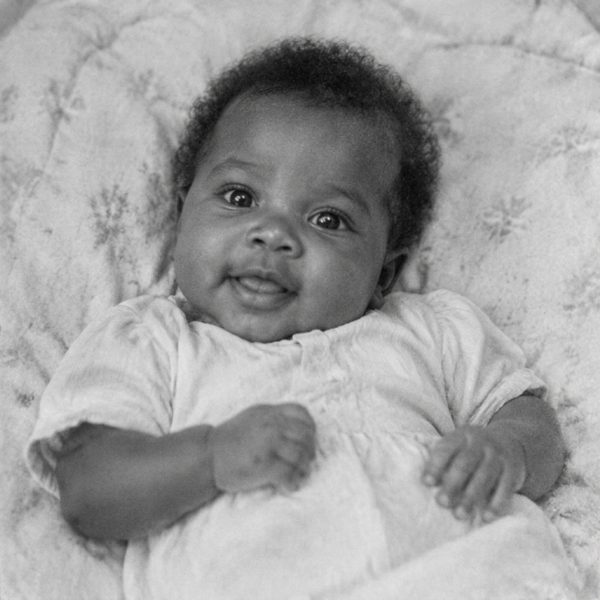 A smiling baby in a black and white photo, restored